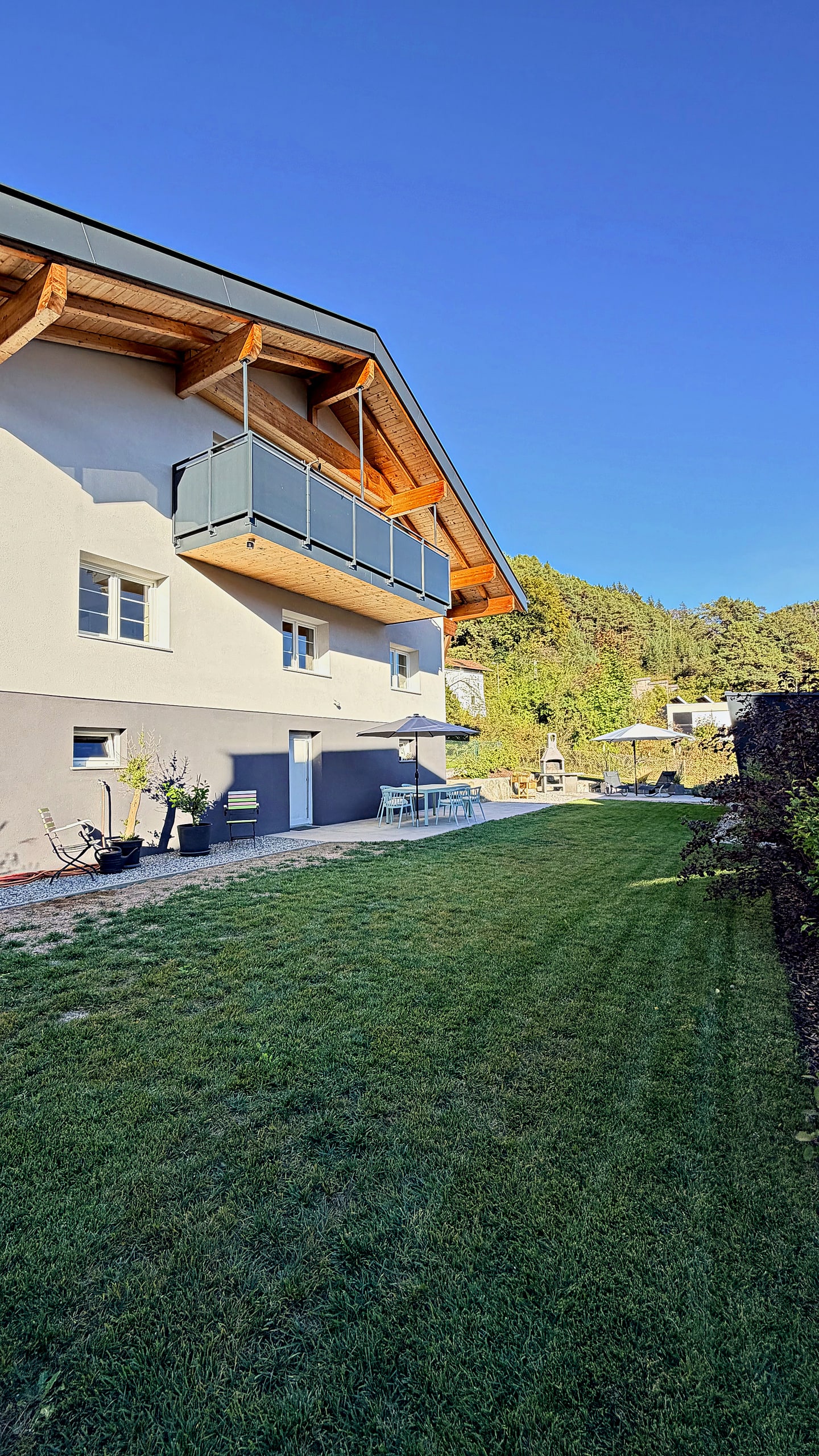 Frisch gemähter Rasen entlang des Hauses unter blauem Himmel
